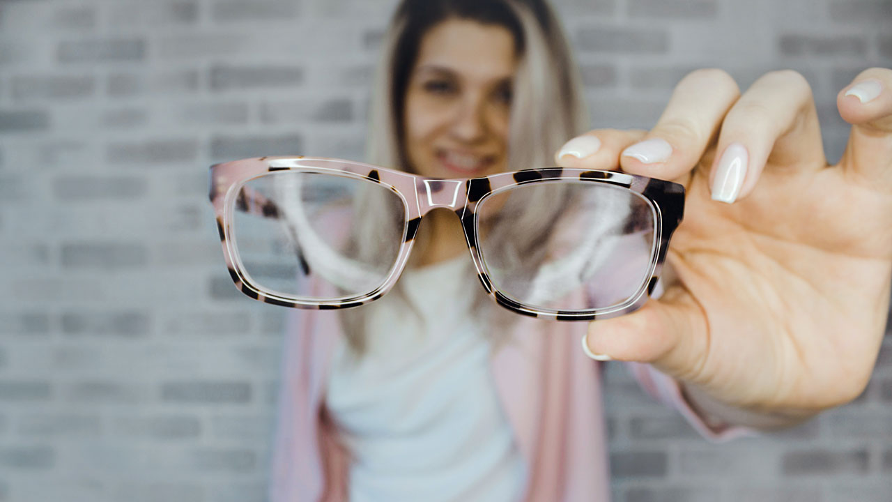 a women holding clean eyeglasses