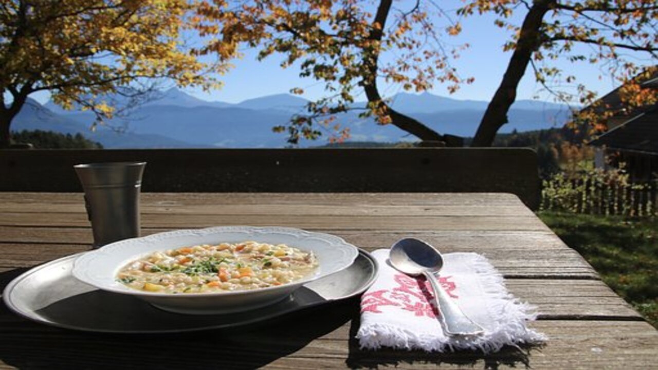 hearty barley, chickpea, and potato soup in a bow with a natural view of mountains