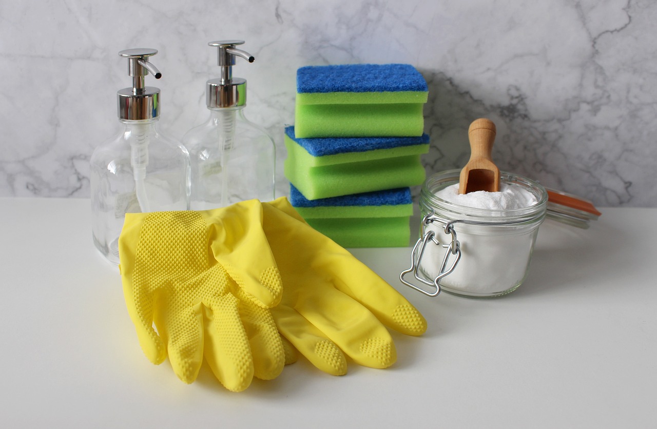 sponge, bottles, coarse salt and gloves are placed on a table