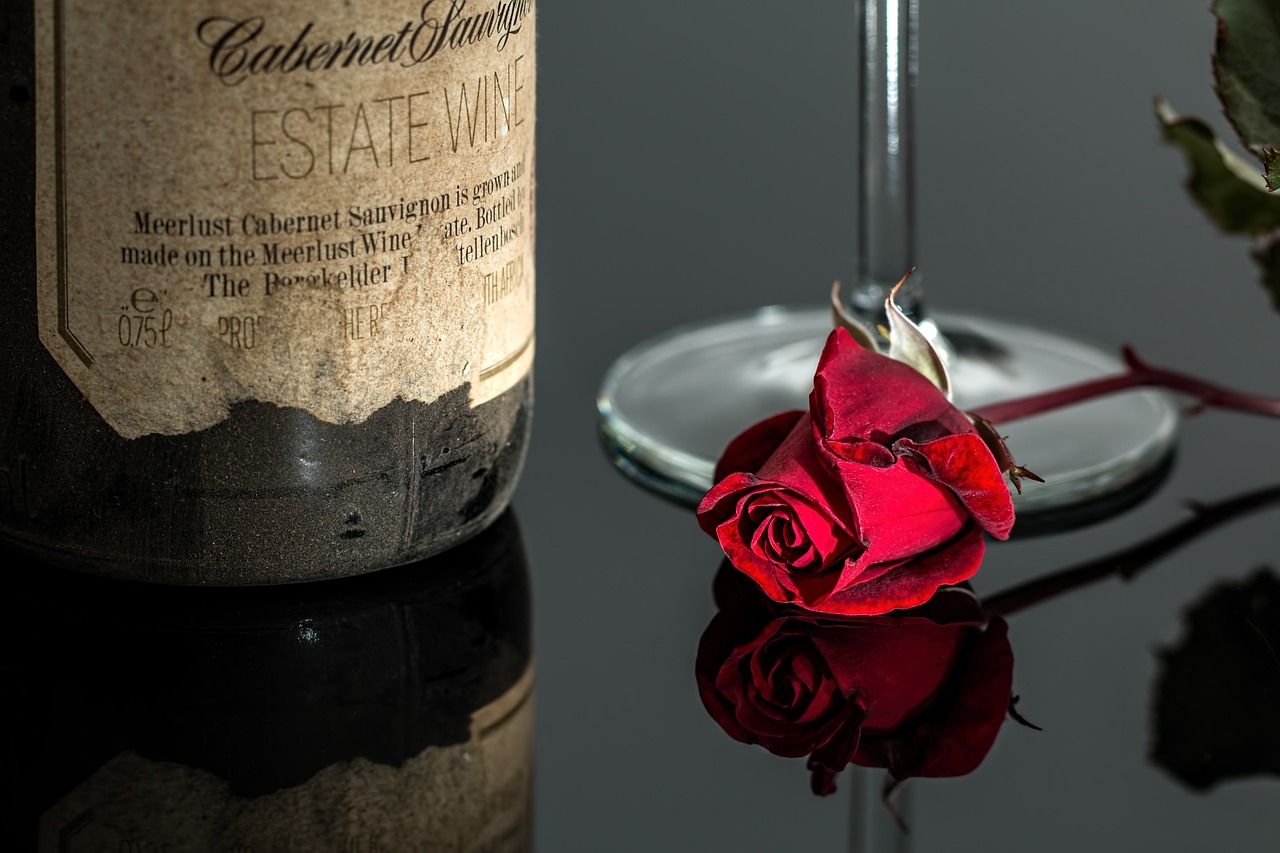 a champagne bottle, a glass, and a rose is placed on a table