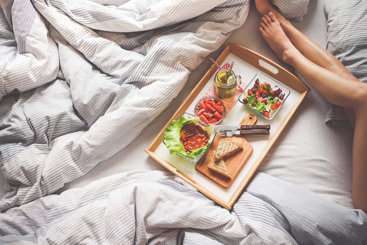 there are clean sheets on the bed and a tray full of breakfast on it