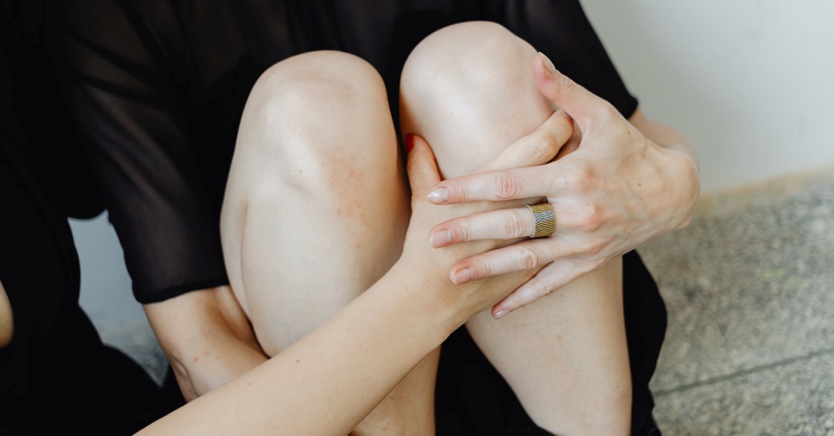 a women is sitting down and checking her knees for any disease