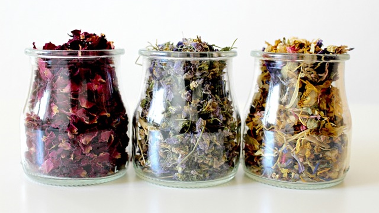 3 jars are placed on a table with different types of flowers in it