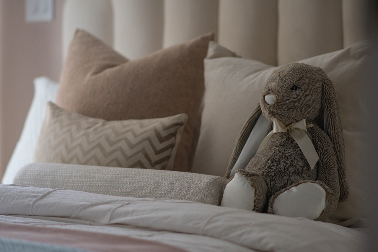 clean pillows on the bed and a cute stuffed rabbit is placed on them