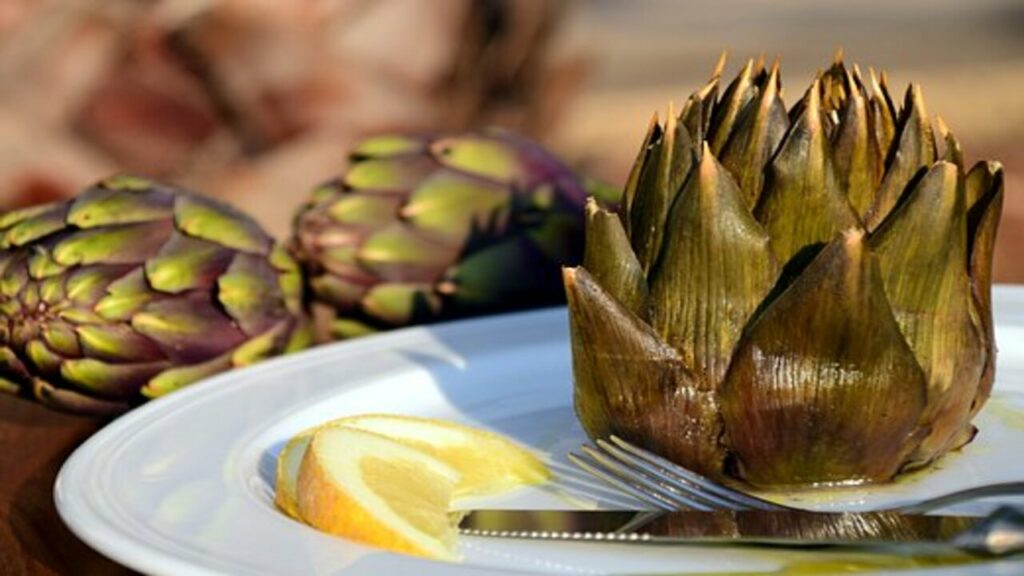 prepared artichoke served in a plate, placed on the table