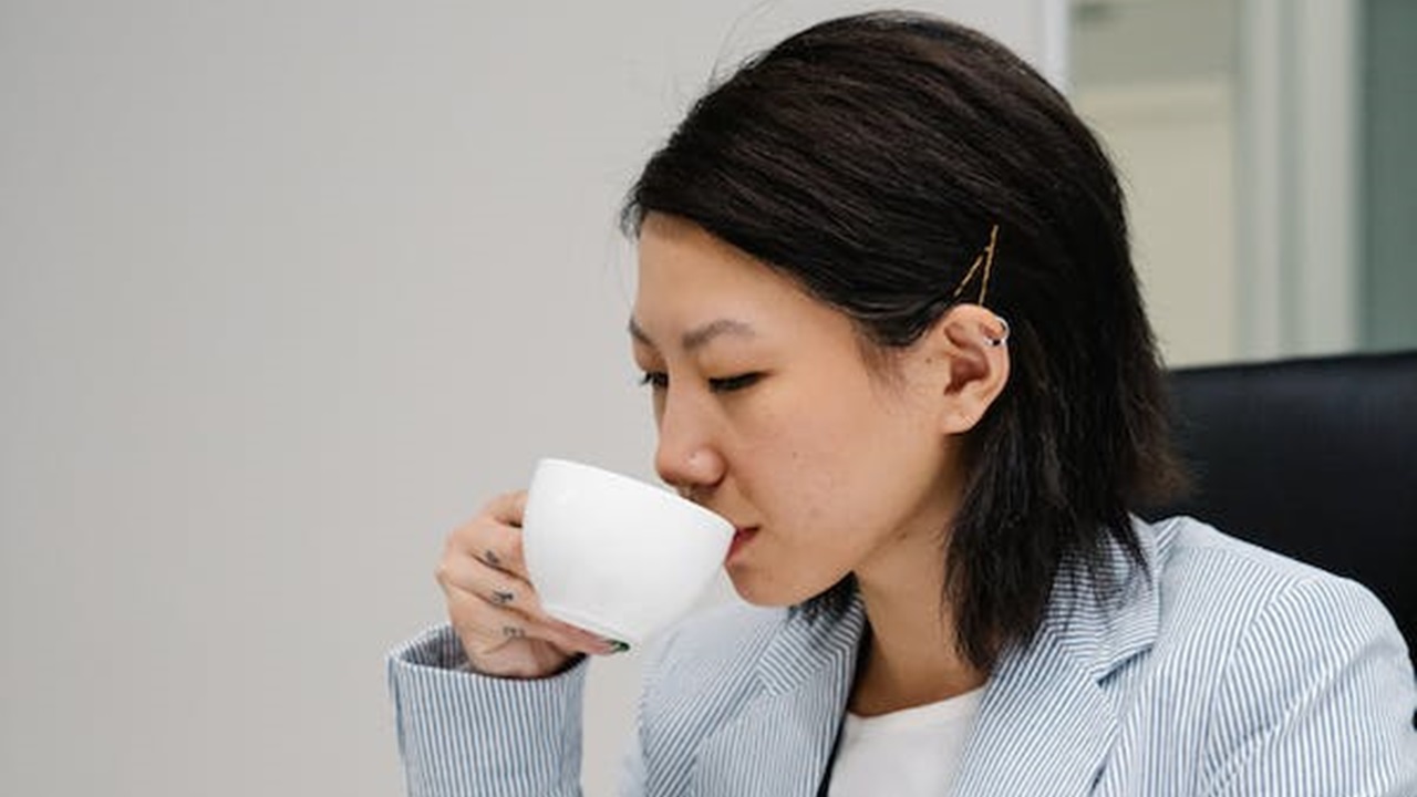 a women is wearing hairpins and drinking tea in her office