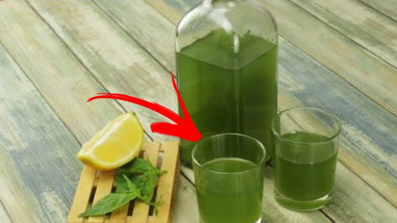 a bottle and two glasses filled with basil  liqueur are placed on a table