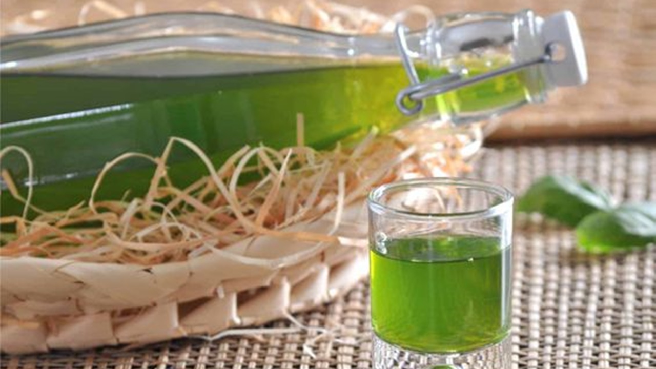 a bottle and a shot filled with basil liqueur is placed on a table