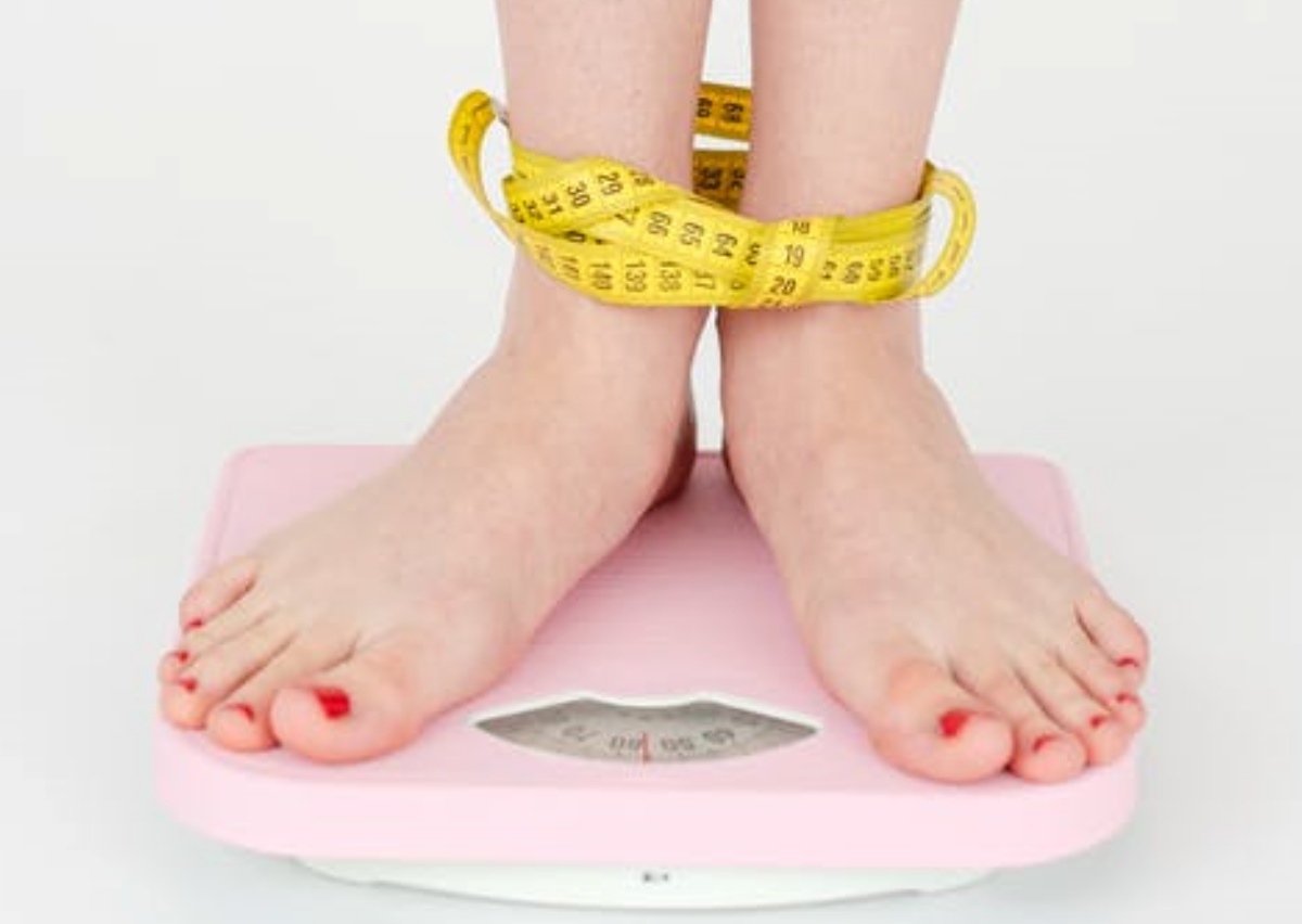 a women is measuring her weight by standing on the measuring table