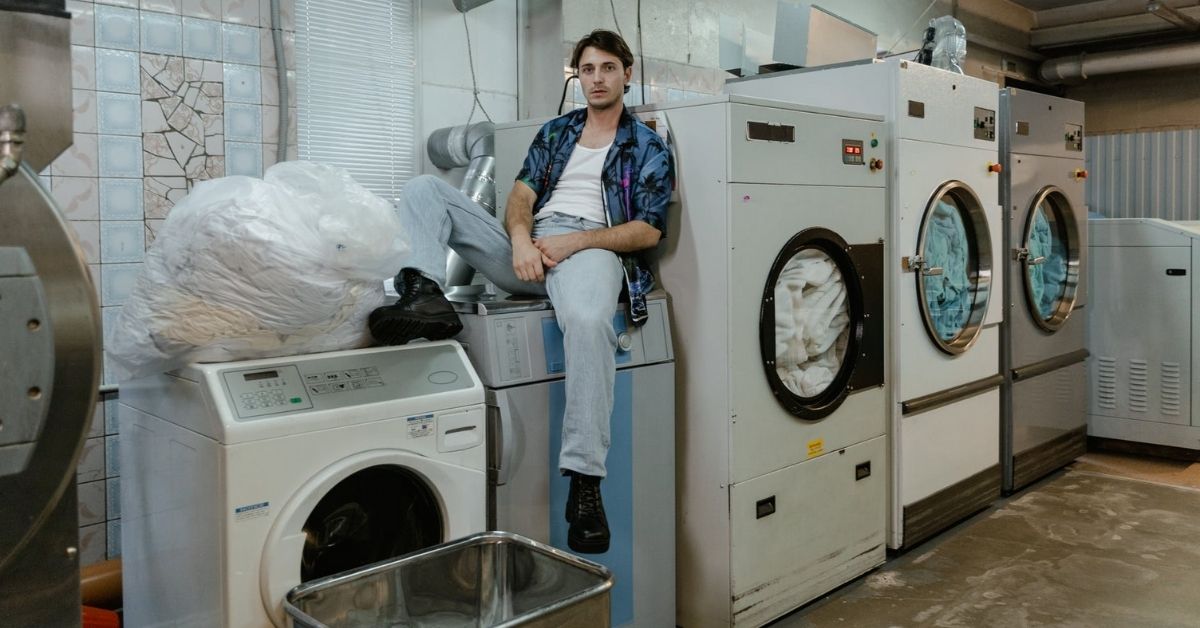 a man is sitting on the washing machine in the laundry