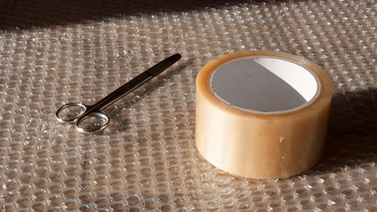 duct tape and scissor placed on a plastic sheet