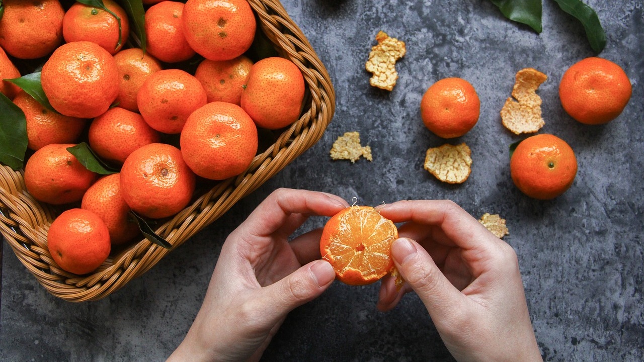 oranges are in the bucket and a girl is peeling one