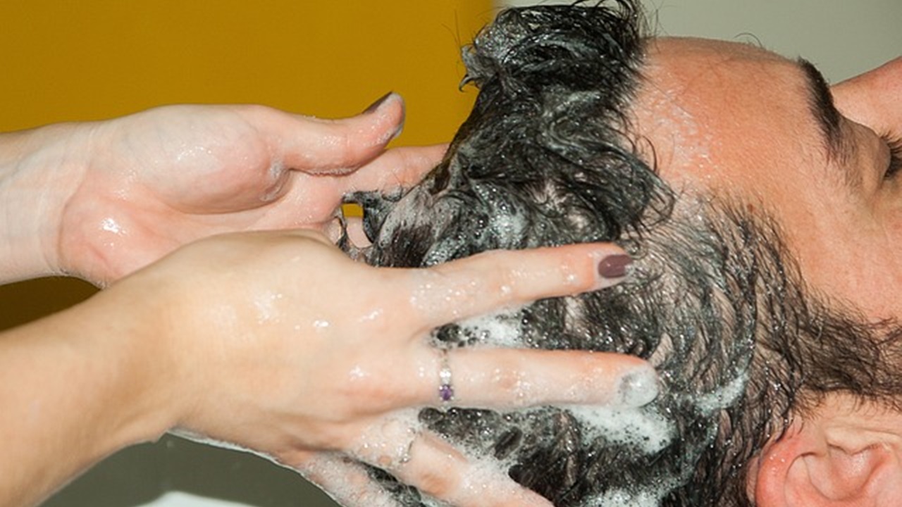 a women is washing hair of a man