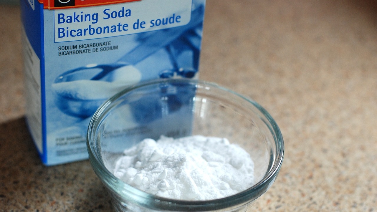 baking soda in a small bowl and a box of it are placed on the table