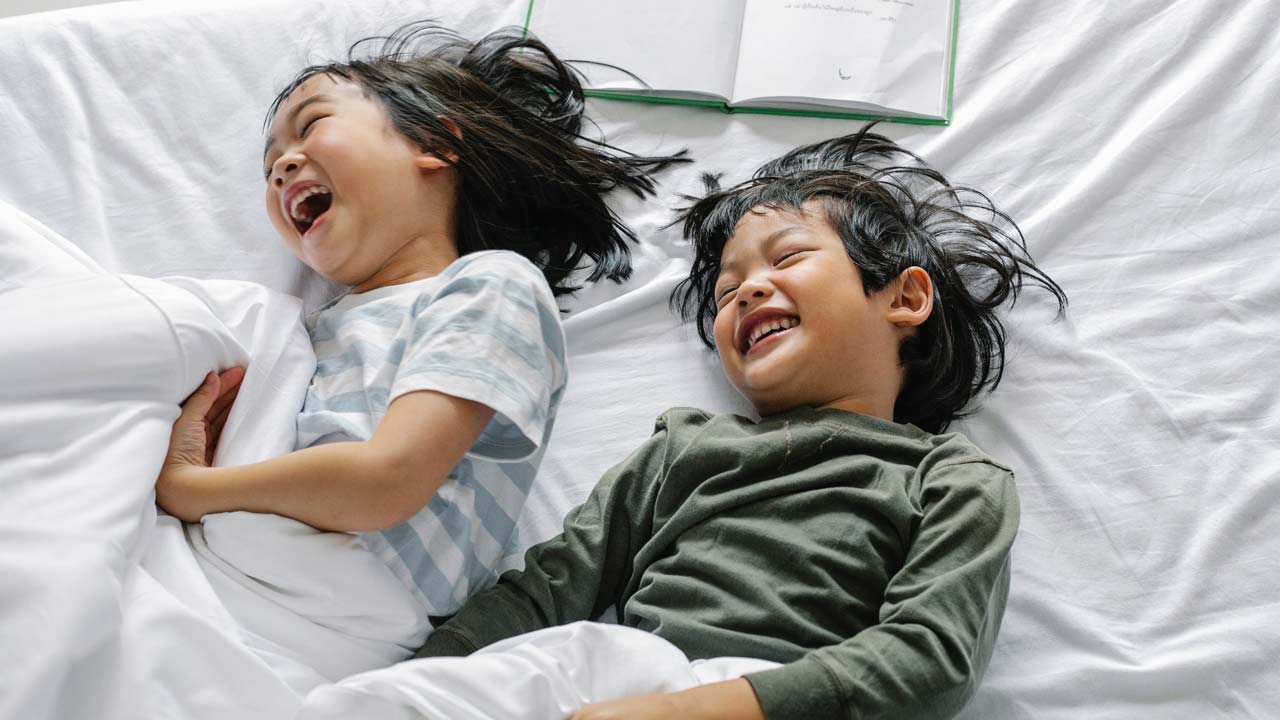 Kids with pajamas are happy on the bed