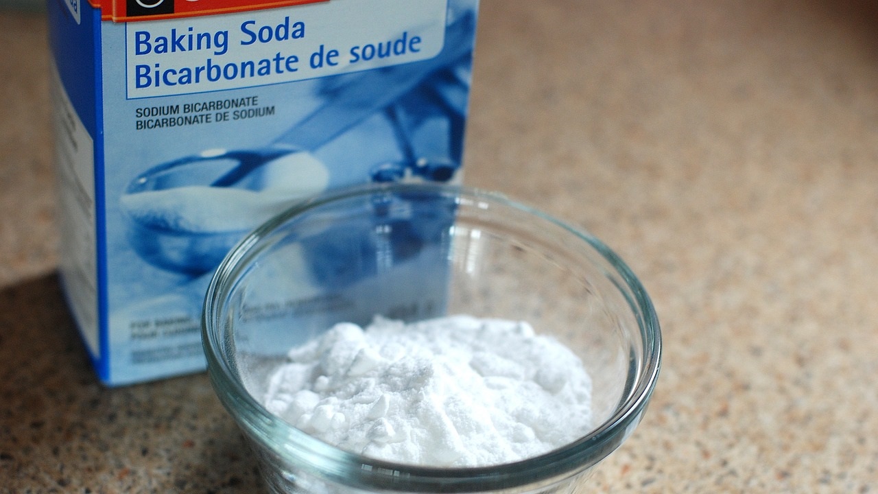 a box of baking soda and some of it in a bowl are placed on the table