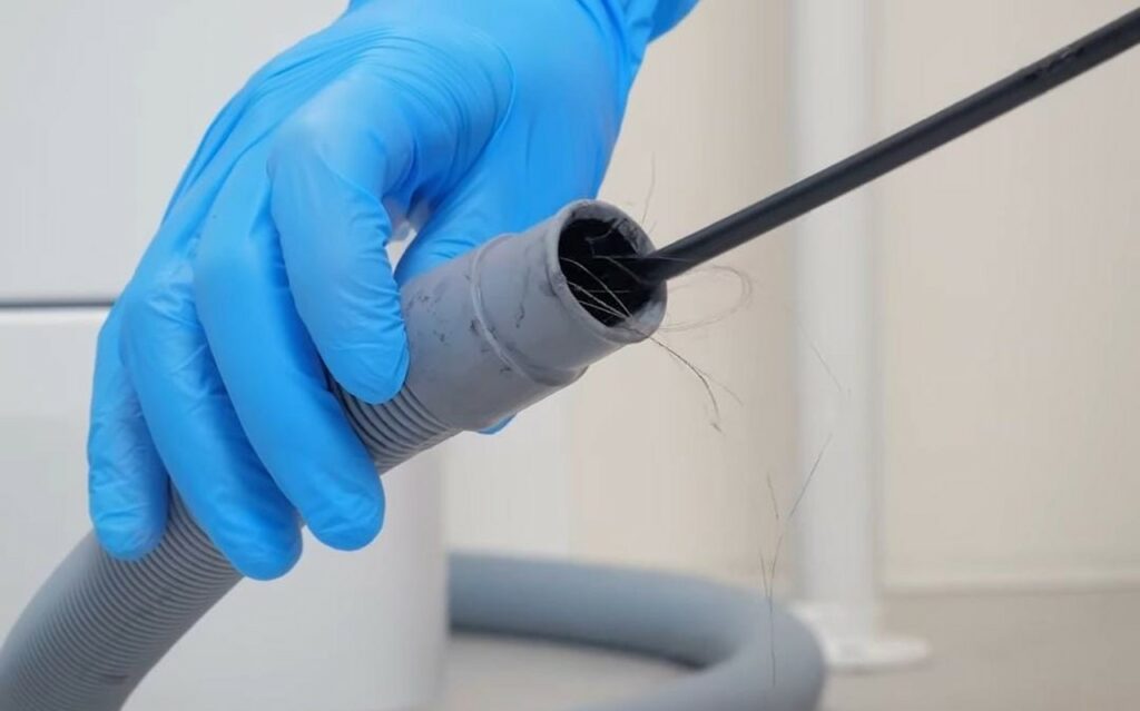 a person is cleaning the drain hose of the washing machine