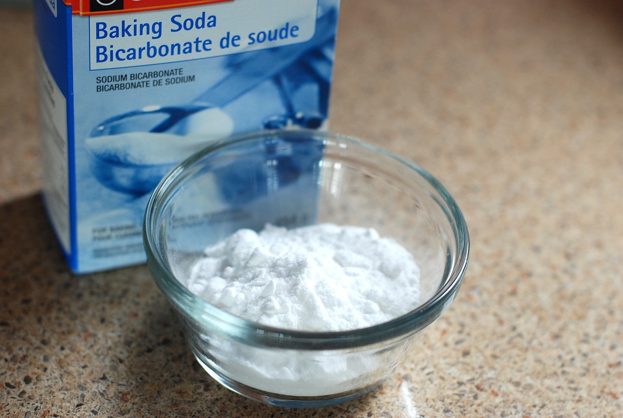 a box of baking soda and some of it in a bowl are placed on the table