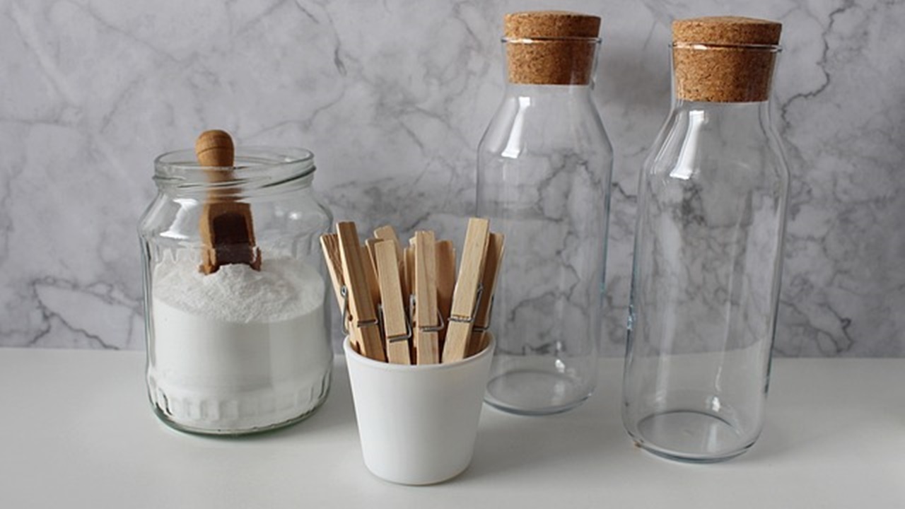 baking soda in a jar and two empty bottles are placed on the table