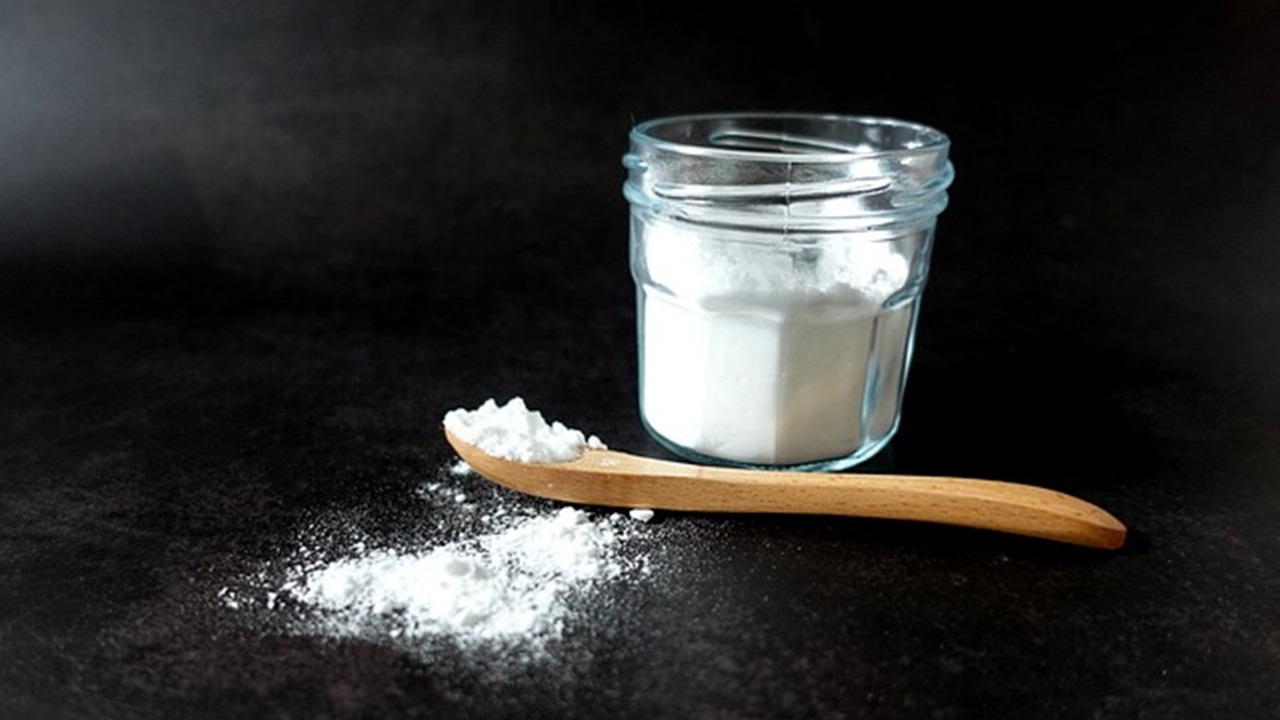 a jar and a spoon placed on the table are filled with baking soda