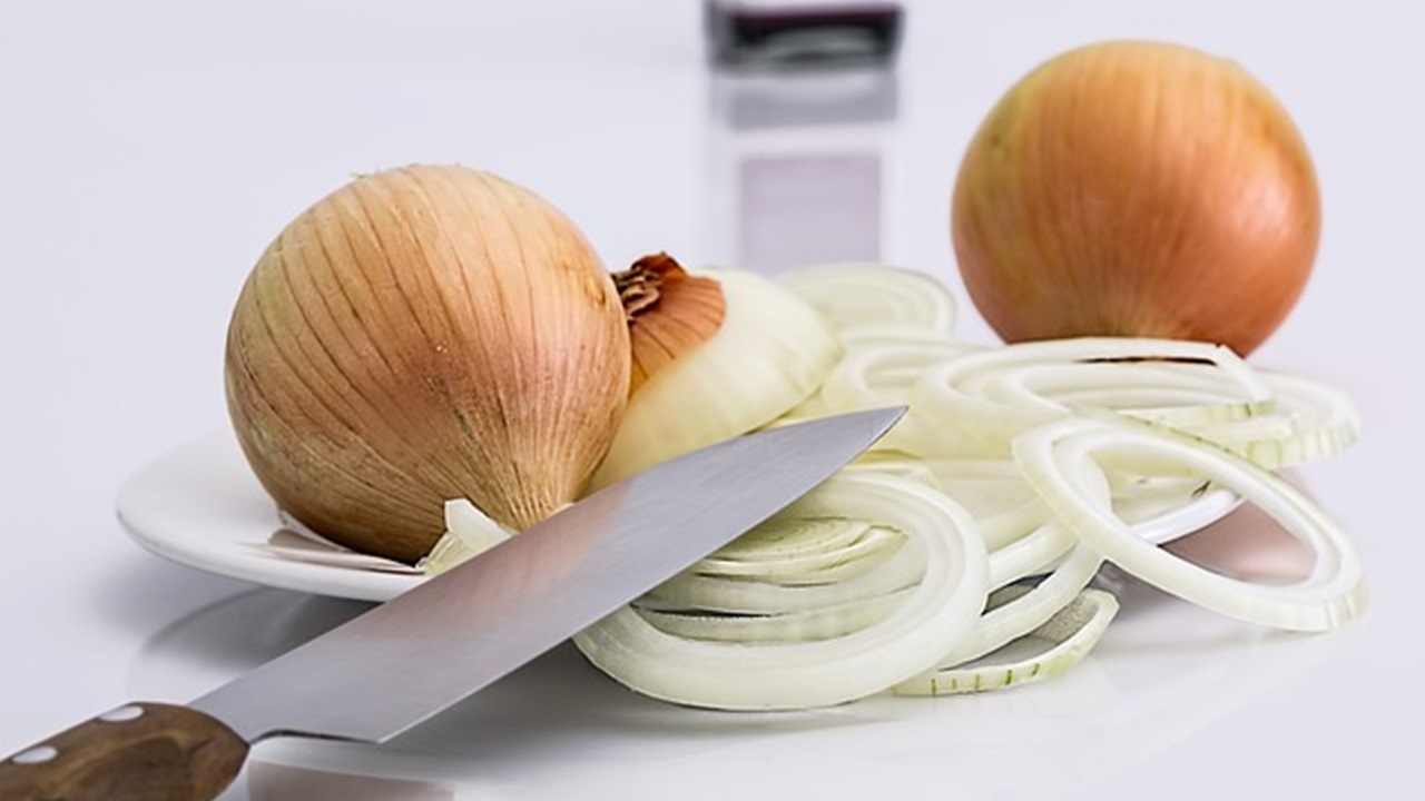 chopped onion on the plate and a knife are placed on the table